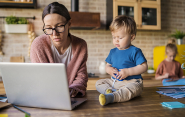 working mom on laptop with two children