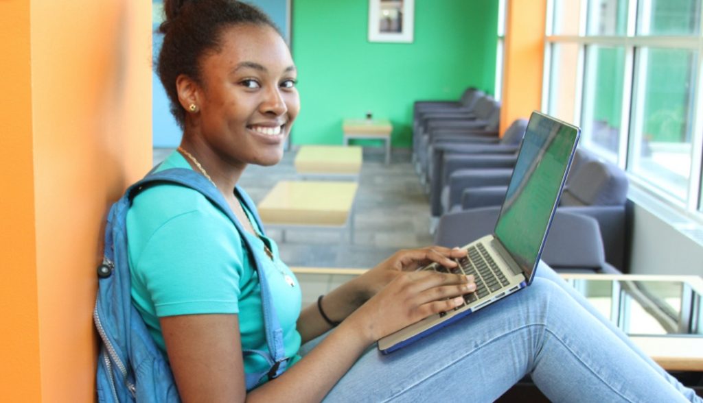 student smiling at camera on laptop